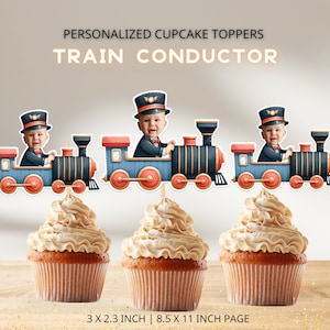 Op de afbeelding: Drie gepersonaliseerde cupcake-toppers met een treinconducteur-thema. Elke topper heeft een blauwe en rode trein met gouden versieringen en een kindergezicht op de bestuurdersstoel. De toppers zijn 7,6 cm bij 5,8 cm en worden afgedrukt op een vel papier van 21,6 cm bij 27,9 cm.
