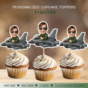 Puede incluir: Adornos personalizados para cupcakes con un bebé en un avión de combate. Los adornos muestran a un bebé con gafas de sol y un traje de vuelo verde. Las magdalenas tienen glaseado blanco y están en un molde marrón. El texto dice "PERSONALIZED CUPCAKE TOPPERS FIGHTER."