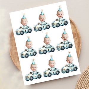 May include: Eight printable stickers featuring a baby in a blue race car with a blue and white chequered flag. The baby is wearing a blue and white party hat and the car has the number 2 on it.