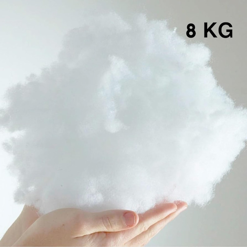 May include: A large amount of white fluffy fiber filling, held in a person's hand. The filling is labeled "8 KG".
