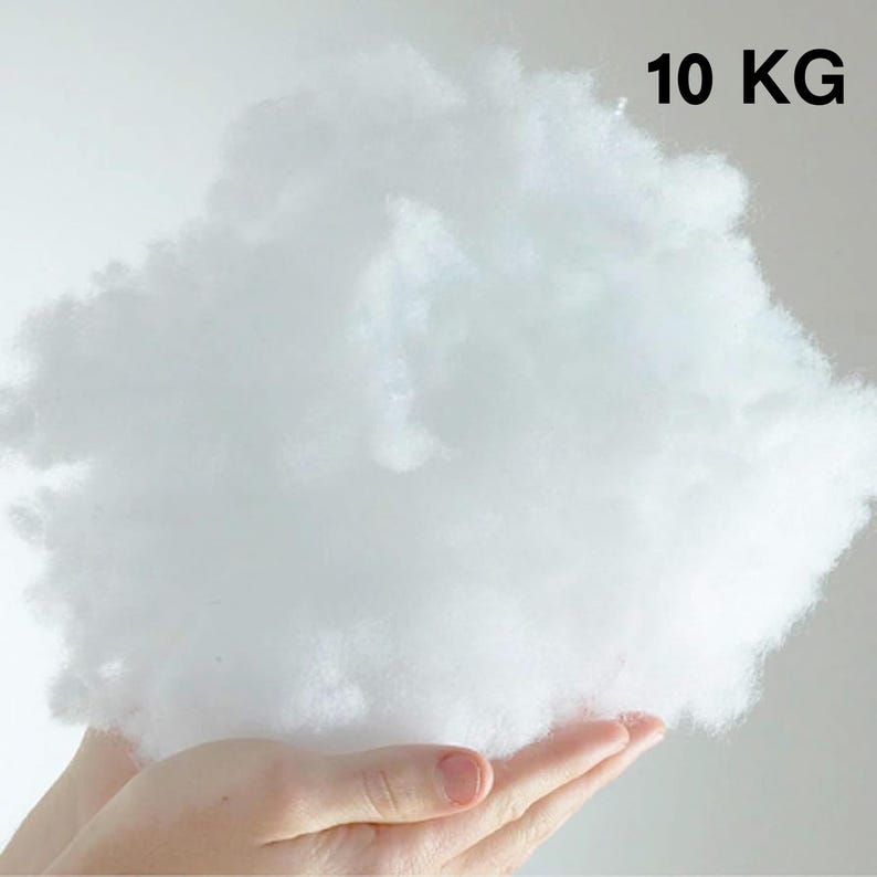 May include: A large, fluffy, white, 10 kg bag of fiberfill. The fiberfill is being held in a person's hand.