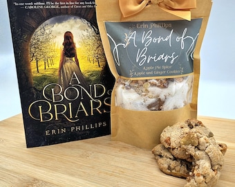 May include: A brown paper bag with a gold ribbon tied around the top. The bag contains apple pie spice and apple and ginger cookies. The bag has a label that says "A Bond of Briars" and "Apple Pie Spice Apple and Ginger Cookies". There is a book with the same title in the background.
