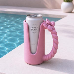 May include: A pink beverage can holder featuring a twisted handle and a decorative bow at the top. The holder contains a silver 330 ml Long Soda Classic can with the text Crisp & Refreshing printed on the front of the aluminum container.