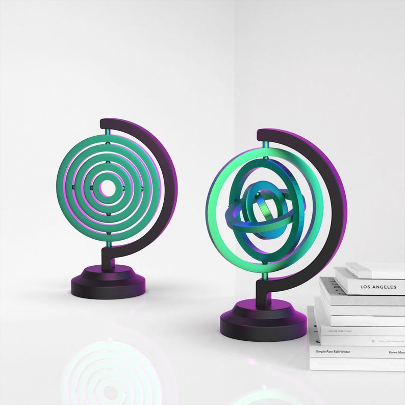 May include: Two decorative globe sculptures with a black stand. The globes are made of metal and have a green and blue iridescent finish. The globe on the left has concentric circles and the globe on the right has a more complex, interwoven design. 3D Gyroscope Fidget, Desktop Gyroscope Model, Desk Toy, Anti Stress - Relax Toy, Sensory Focus, Ready to Print, 3D STL File Digital Download