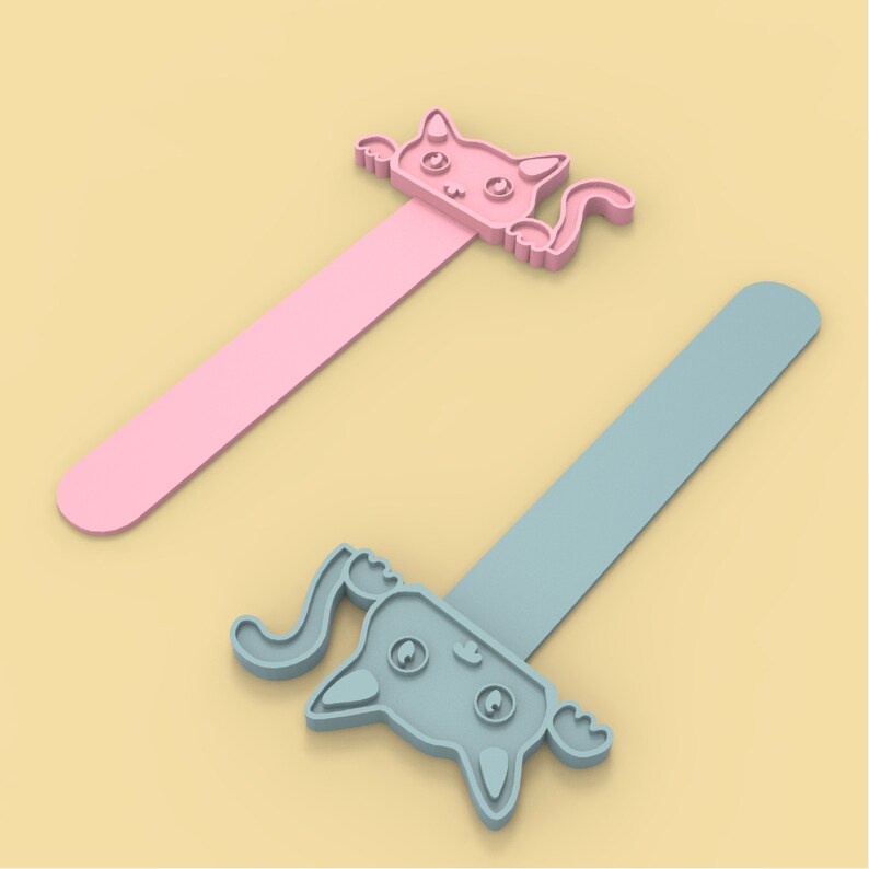 以下が含まれることがあります： ピンクとブルーの猫の形をした磁石のブックマークが2つ。ピンクのブックマークは、黒い目とピンクの鼻を持つ白い猫の顔をしています。ブルーのブックマークは、黒い目と青い鼻を持つ白い猫の顔をしています。