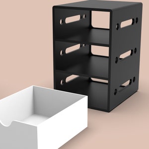 Puede incluir: Una estanter&iacute;a negra de tres niveles con lados abiertos y un caj&oacute;n blanco. La estanter&iacute;a tiene tres estantes y est&aacute; hecha de madera. El caj&oacute;n est&aacute; hecho de pl&aacute;stico.