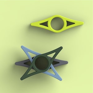 A top-down view shows four colorful plastic book page holders shaped like rhombuses with center rings, set against a light green background.