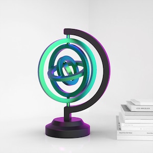 Puede incluir: Un soporte de globo de metal negro con un dise&ntilde;o de esfera de capas multicolores. La esfera est&aacute; hecha de anillos verdes, azules y morados.