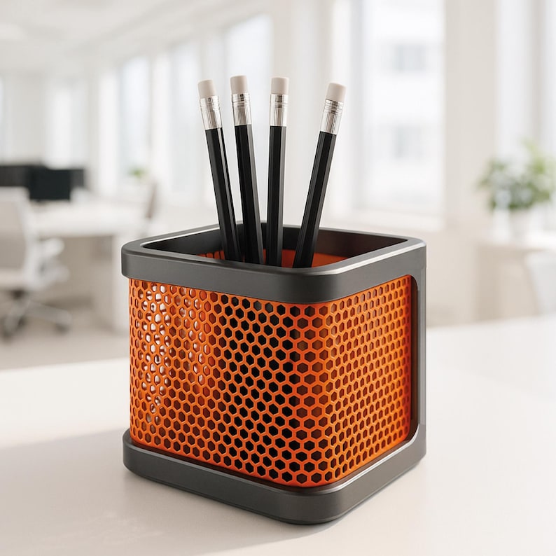May include: A modern orange and black pencil holder with a honeycomb design, holding four black pencils with white erasers. The pencil holder is square and sits on a white surface, ideal for office or desk organization.