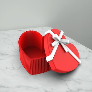 May include: A red heart-shaped box with a white ribbon and bow. The box is open and the inside is empty.