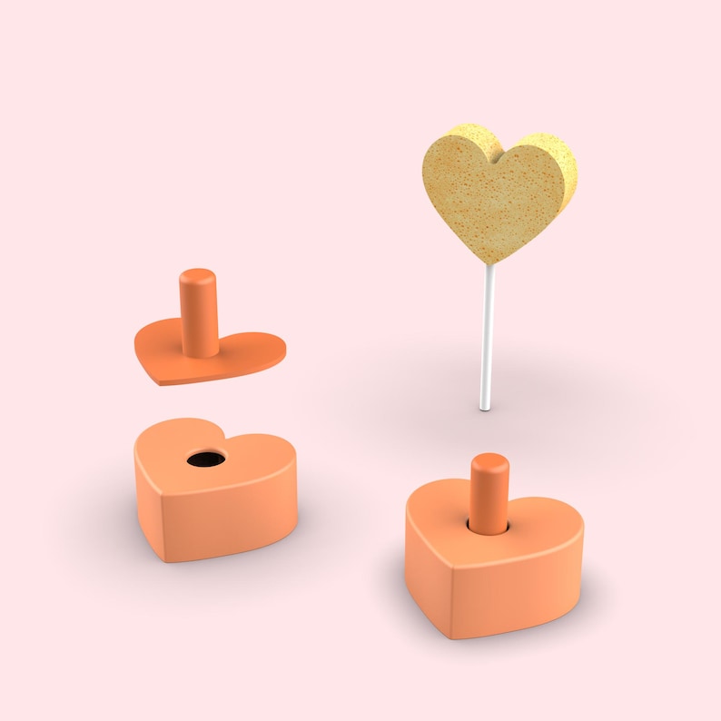 Pode incluir: Um conjunto de tr&ecirc;s componentes laranja em forma de cora&ccedil;&atilde;o e um topo amarelo em forma de cora&ccedil;&atilde;o num pau branco. Dois dos cora&ccedil;&otilde;es laranja apresentam um pino cil&iacute;ndrico central, enquanto o terceiro cora&ccedil;&atilde;o laranja tem um orif&iacute;cio.