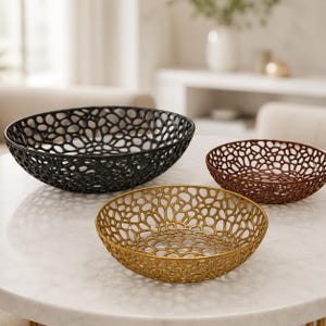 May include: Three round bowls featuring an intricate, open-work lattice pattern. The largest bowl is black, the medium bowl is gold, and the smallest bowl is a deep bronze colour. Each bowl has a wide, shallow shape with a continuous web-like design.