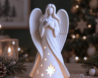 May include: A white ceramic angel figurine with large wings, holding a star against its chest. The base of the gown features cut-out star shapes of varying sizes that emit a warm, internal glow, creating a soft light effect on the surface.