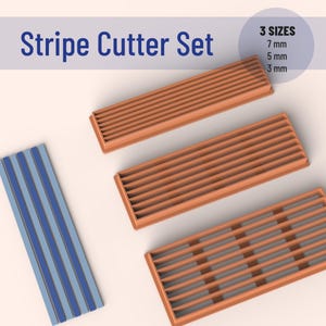 Peut inclure: Ensemble de trois découpeurs de rayures en plastique orange. Les découpeurs mesurent 7 mm, 5 mm et 3 mm de large. Les découpeurs sont sur une surface blanche.