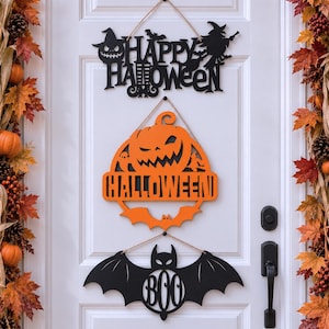 May include: Three hanging Halloween signs made of wood. The top sign is black with the text HAPPY HALLOWEEN, a pumpkin, and a witch. The middle sign is orange, shaped like a pumpkin with the word HALLOWEEN. The bottom sign is a black bat with BOO.