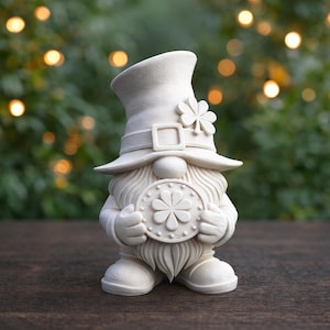 Könnte beinhalten: Cremefarbene Zwergenfigur mit hohem Hut, Schnalle und Kleeblatt-Akzent. Der Zwerg hält ein rundes Emblem mit Kleeblatt-Design. Die Figur hat einen langen Bart und steht auf einer Holzoberfläche.