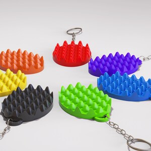 May include: A collection of colorful, textured keychains in various colors including red, orange, yellow, green, blue, purple, and black. Each keychain has a unique, spiky design and is attached to a silver chain and ring.