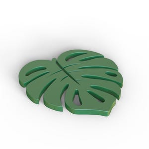 Puede incluir: Un objeto decorativo en forma de hoja de Monstera verde s&oacute;lido. La hoja tiene varias secciones recortadas y una vena central prominente. El art&iacute;culo probablemente est&aacute; hecho de un material s&oacute;lido y est&aacute; dise&ntilde;ado para ser un acento decorativo.