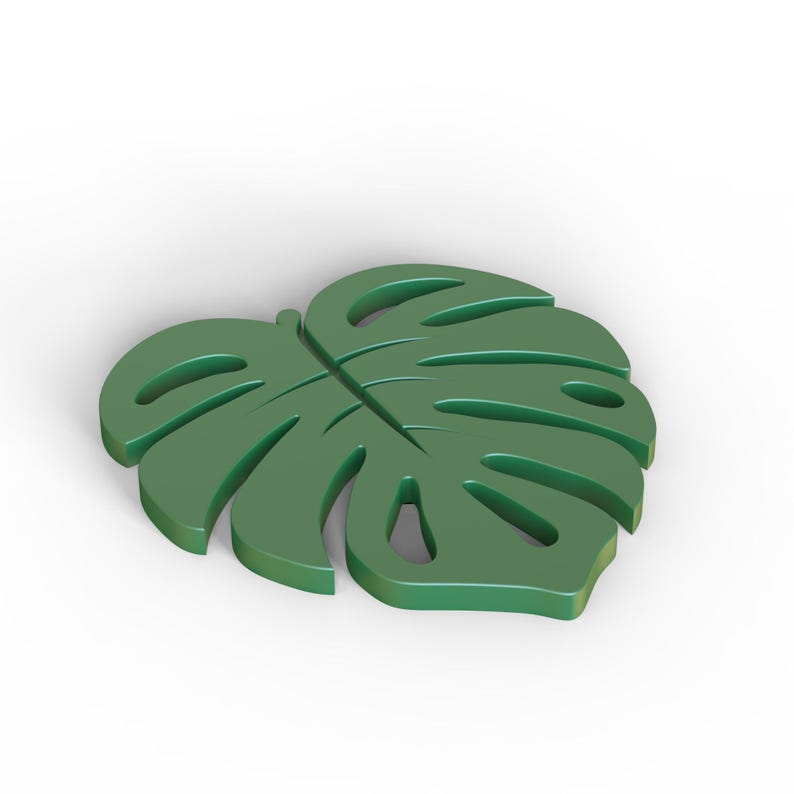 Puede incluir: Un objeto decorativo en forma de hoja de Monstera verde s&oacute;lido. La hoja tiene varias secciones recortadas y una vena central prominente. El art&iacute;culo probablemente est&aacute; hecho de un material s&oacute;lido y est&aacute; dise&ntilde;ado para ser un acento decorativo.