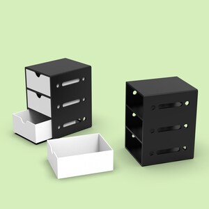 Puede incluir: Dos unidades de almacenamiento negras con cajones blancos. Una unidad tiene tres estantes y la otra tiene dos cajones y un estante. Los cajones est&aacute;n abiertos y vac&iacute;os.