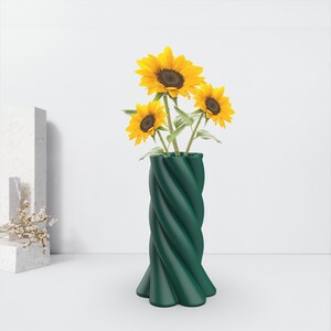 May include: A green ceramic vase with a twisted design holds a bouquet of yellow sunflowers.