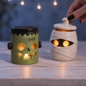 Pu&ograve; includere: Due portacandele in ceramica a forma di personaggi di Halloween. Uno &egrave; un mostro di Frankenstein verde con coperchio nero e bulloni, l'altro &egrave; una mummia color crema con coperchio rimovibile. Entrambi presentano aperture per la luce.