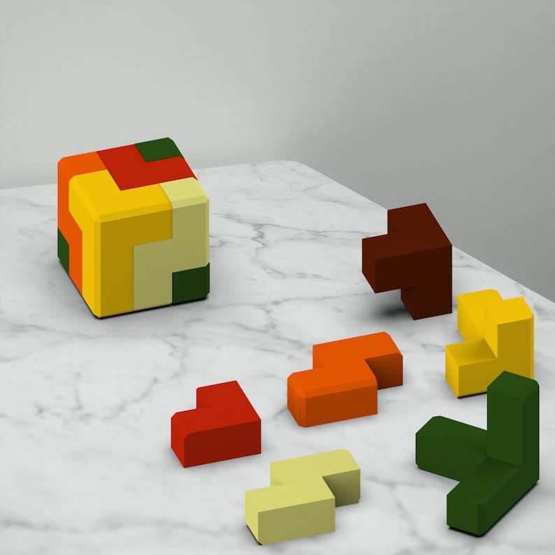 Puede incluir: Un conjunto de bloques de rompecabezas de madera de colores en varias formas, incluyendo un cubo, un coraz&oacute;n y algunas piezas en forma de L. Los bloques est&aacute;n dispuestos sobre una superficie de m&aacute;rmol blanco.