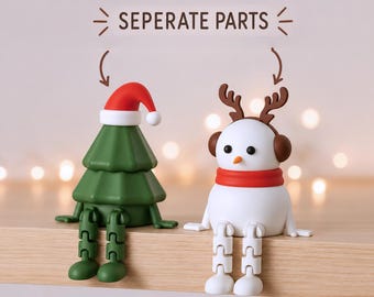 Puede incluir: Dos pequeñas figuras, un árbol de Navidad verde con un gorro de Papá Noel rojo y un muñeco de nieve blanco con astas de reno y orejeras marrones, ambos con piernas articuladas y el texto SEPERATE PARTS encima.