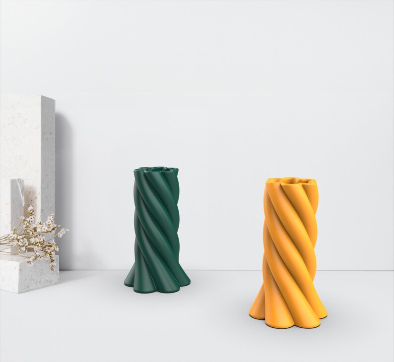 May include: Two decorative twisted candles, one green and one yellow, on a white surface.