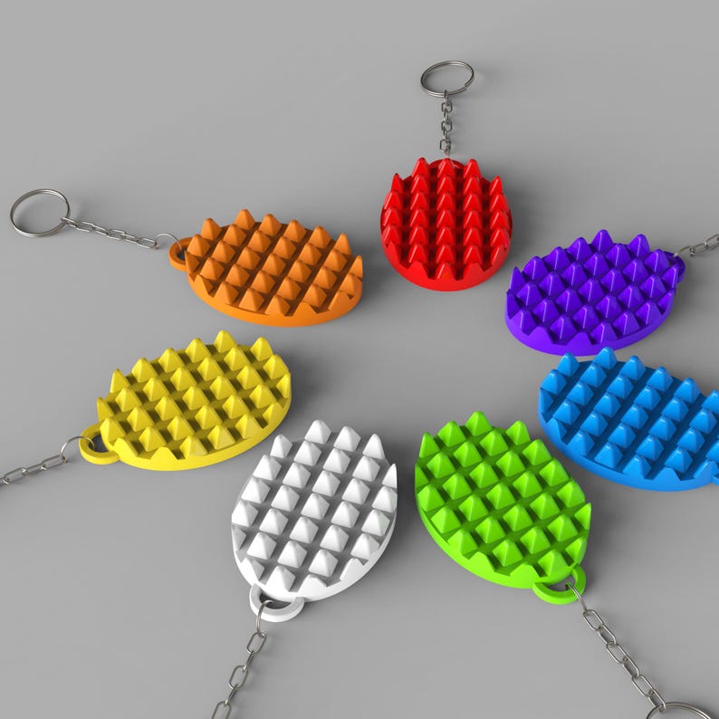 May include: A collection of colorful, textured keychains in orange, red, purple, blue, green, white, and yellow. Each keychain has a chain and a ring. The keychains have a textured surface with a grid of small, raised triangles.