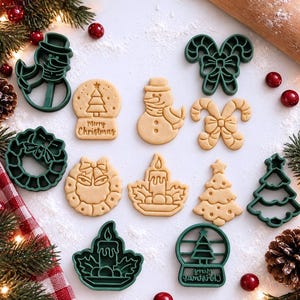 May include: A collection of dark green plastic cookie cutters and matching baked sugar cookies in various holiday shapes including a snowman, candy canes, a wreath, a candle, a Christmas tree, and a snow globe with the text Merry Christmas.