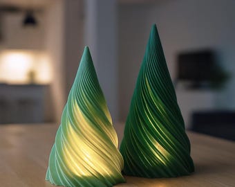 May include: Two green, cone-shaped decorative lights with a spiral design. The lights are illuminated from within, creating a warm glow. The lights are placed on a wooden surface.