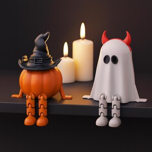 May include: Halloween-themed figurines of a pumpkin wearing a witch hat and a ghost with red horns. The pumpkin has orange legs and the ghost has white legs. Lit candles are in the background.