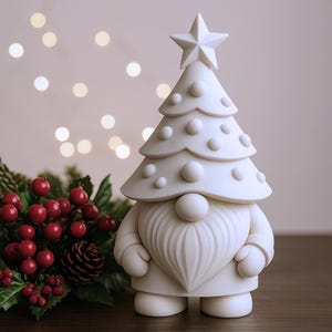Op de afbeelding: Een witte kerstkabouterfiguur met een boomvormige hoed en een ster. De kabouter heeft een grote, hartvormige baard en staat naast een feestelijk arrangement van rode bessen en groen. Een decoratief vakantieartikel.
