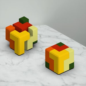 Puede incluir: Dos rompecabezas de madera coloridos hechos de cubos que se entrelazan. Los rompecabezas son en tonos de rojo, naranja, amarillo y verde. Los rompecabezas est&aacute;n sobre una superficie de m&aacute;rmol blanco.