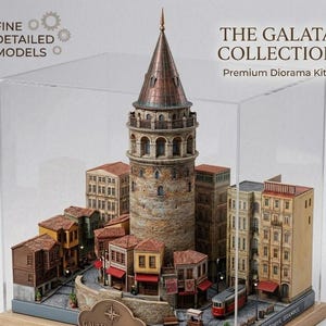 May include: A detailed diorama kit of the Galata Tower and surrounding buildings, displayed in a clear acrylic case. The model features a copper-colored tower, detailed facades, and the text "THE GALATA COLLECTION".
