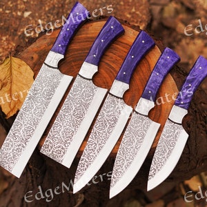 May include: Five kitchen knives with purple handles and intricate floral patterns etched into the blades. The knives are arranged on a wooden surface.