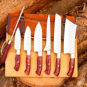 May include: Set of seven kitchen knives with red and brown handles, displayed on a wooden cutting board. The knives are arranged in a row, with the largest knife at the top and the smallest knife at the bottom. The knives are all sharp and have a diamond-shaped pattern on the blades.