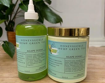 Op de afbeelding: Twee groene en witte flessen met Honeysuckle Hemp Green Tea Agapé Derma producten. De fles links is een vloeibaar product van 14 oz. De fles rechts is een crèmeproduct van 2 oz. Beide flessen hebben gouden deksels en tonen een groene theekop met een groen bladdesign.