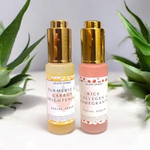 May include: Two facial serum bottles with gold-colored caps. One bottle is yellow with the text "Turmeric & Carrot Brightening Facial Serum." The other is pink with the text "Rice Collagen & Pomegranate Facial Serum."