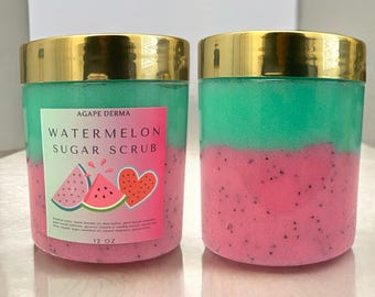 May include: Two jars of watermelon sugar scrub with gold lids. The jars are filled with a green and pink scrub. The label on the front of the jar says "Agape Derma Watermelon Sugar Scrub" and features a watermelon and heart graphic. The jar is 12 oz.