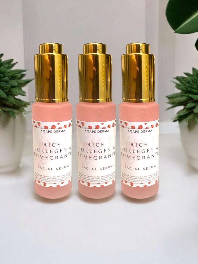 Puede incluir: Tres frascos de s&eacute;rum facial rosa con tapas doradas. Cada frasco tiene una etiqueta blanca con el texto "RICE COLLAGEN & POMEGRANTE FACIAL SERUM" y un dise&ntilde;o de granada. Los frascos est&aacute;n dispuestos en fila.