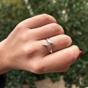 Peut inclure: Une bague en argent avec un design incurvé unique. La bague est ouverte et s'enroule autour du doigt.