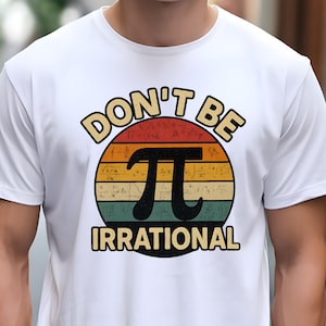 May include: White t-shirt with a retro design featuring the text "DON'T BE IRRATIONAL" above a black pi symbol. The pi symbol is set against a colorful striped background resembling a sunset.