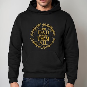 May include: Black hooded sweatshirt with a gold graphic of the One Ring from The Lord of the Rings. The graphic says "One Dad To Rule Them All".
