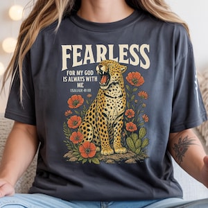 May include: Dark gray t-shirt with a graphic of a cheetah, flowers, and the text "FEARLESS FOR MY GOD IS ALWAYS WITH ME ISAIAH 41:10". The cheetah has a yellow and black spotted pattern. Orange flowers and green cacti surround the cheetah.