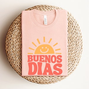 a pink t - shirt that says buenos dias on it