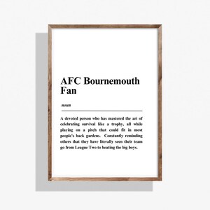 Könnte beinhalten: Gerahmter Druck mit weißem Hintergrund und schwarzem Text. Der Text lautet "AFC Bournemouth Fan" mit einer Definition darunter. Der Rahmen besteht aus hellem Holz.