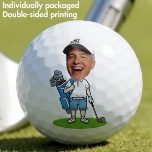 Könnte beinhalten: Weißer Golfball mit einem Cartoon-Bild eines lächelnden Mannes mit Baseballkappe und Golfschlägern. Der Golfball hat den Text "Individuell verpackt beidseitiger Druck". Der Hintergrund ist grün.