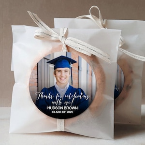 Peut inclure: Des sachets cadeaux blancs avec un autocollant rond repr&eacute;sentant un dipl&ocirc;m&eacute; portant une toque et une robe bleues. L'autocollant indique "Merci d'avoir c&eacute;l&eacute;br&eacute; avec moi !"  "HUDSON BROWN"  "CLASSE DE 2025"